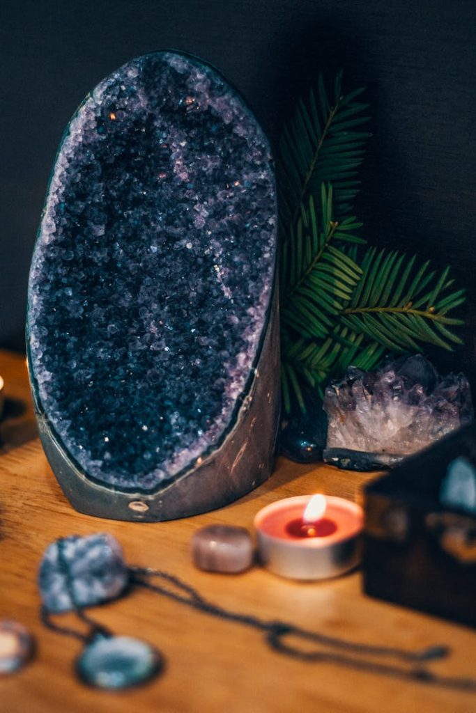 geode-rock-on-the-table-3610682 Serene scene with a large amethyst geode, teardrop candles, and lush greenery. Perfect for spa and relaxation themes.